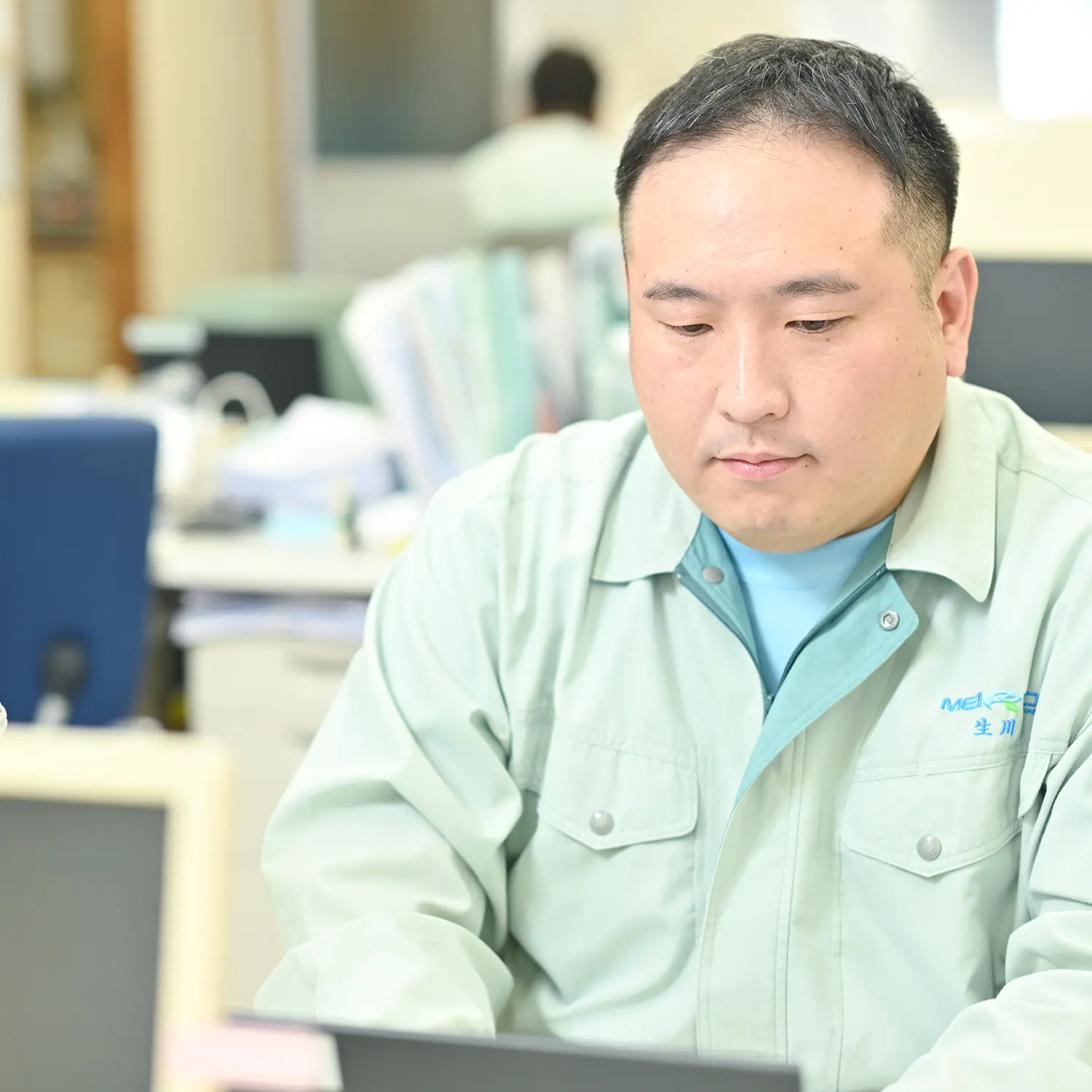 作業着でパソコン作業をする男性