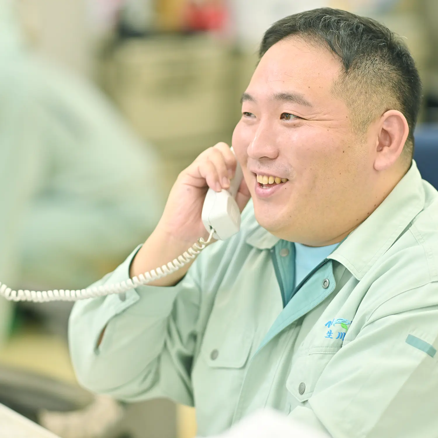 作業着で電話にでる男性