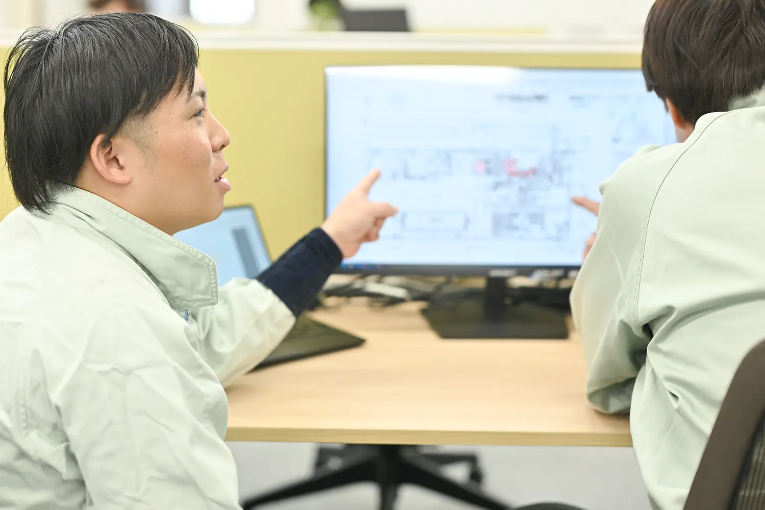 対話する作業着の男性